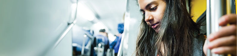 Photo of a young woman looking at her phone on public transport